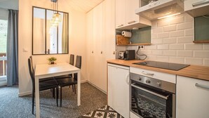 A compact kitchen with a dining table, chairs, a built-in oven, and a microwave.