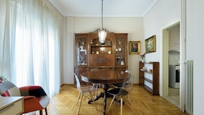 A dining room with a wooden table, clear chairs, a chandelier, and a wooden cabinet with glass doors. - Cosy 2BR flat - metro station & hospital (Athens)