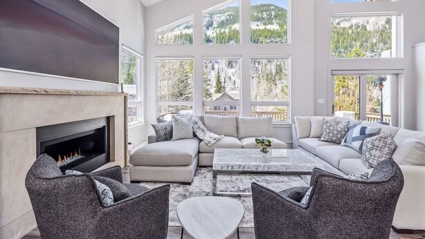 A modern living room with a fireplace, large windows, and a cozy seating area.