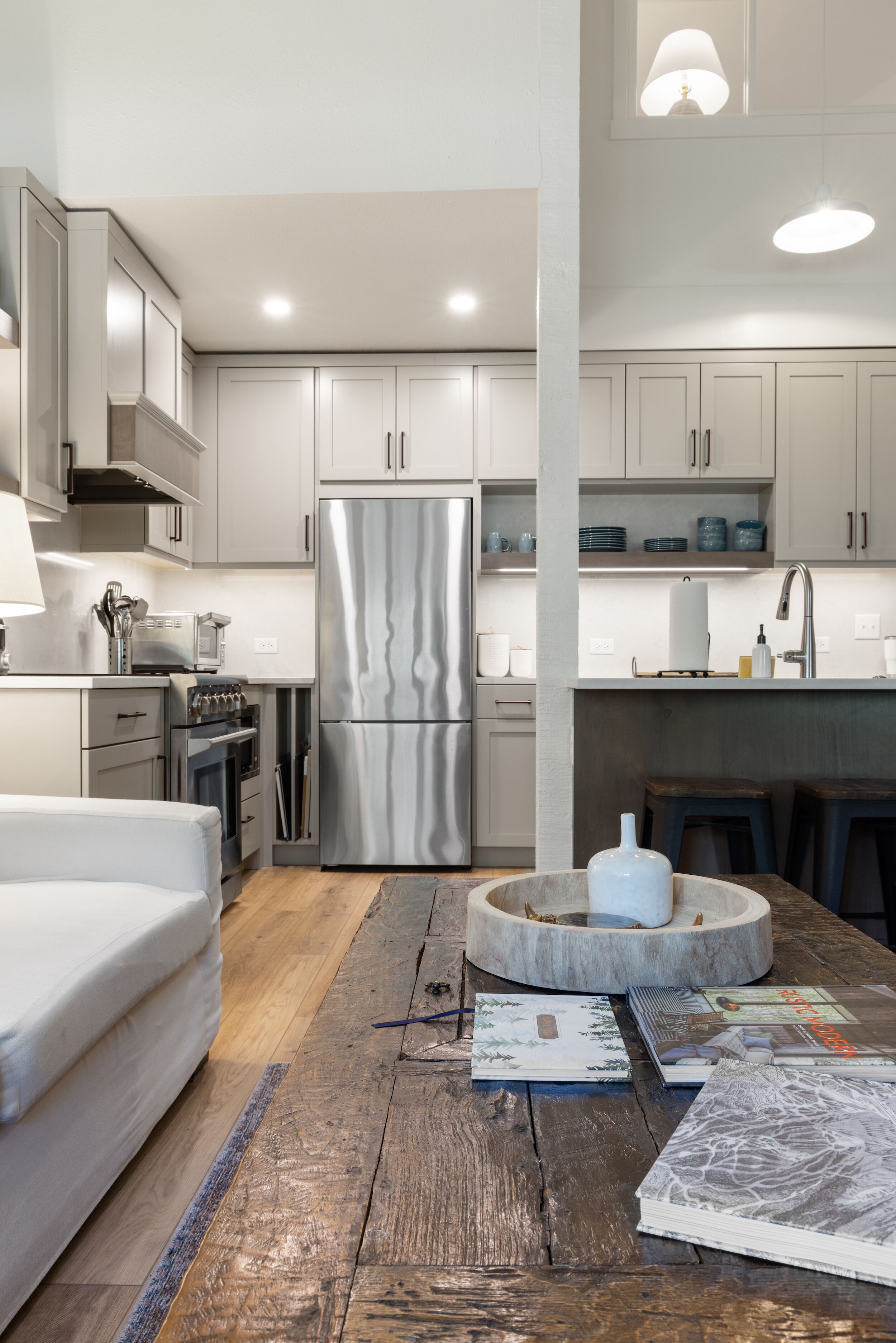A modern kitchen with stainless steel appliances, wooden flooring, and a central island.