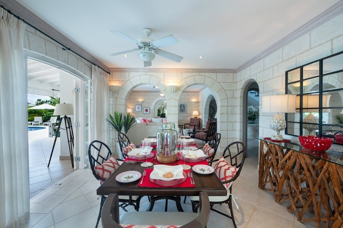 A dining area with a table set for four, surrounded by chairs, a glass coffee table, and a decorative centerpiece.
