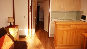 A compact kitchen with wooden cabinets and a microwave.
