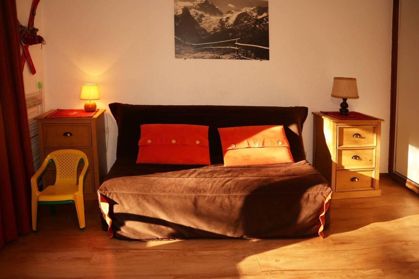 Une chambre à coucher comprenant un lit, des tables de chevet, une chaise et un tableau accroché au mur.