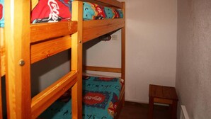 A bunk bed with colorful bedding and a small wooden stool.
