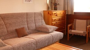 A living room with a sofa, a wooden coffee table, a wooden dresser, and a chair. - Ski-in/ski-out & foot of the slopes, 6th floor, balcony, tv, ski locker, 18m², Les Orres (Les Orres)