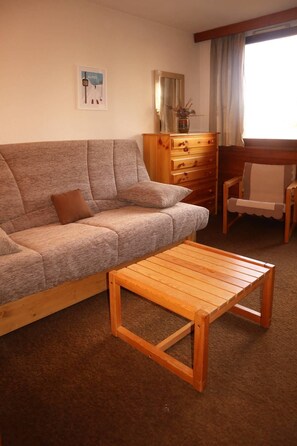 A living room with a sofa, a wooden coffee table, a wooden dresser, and a chair.