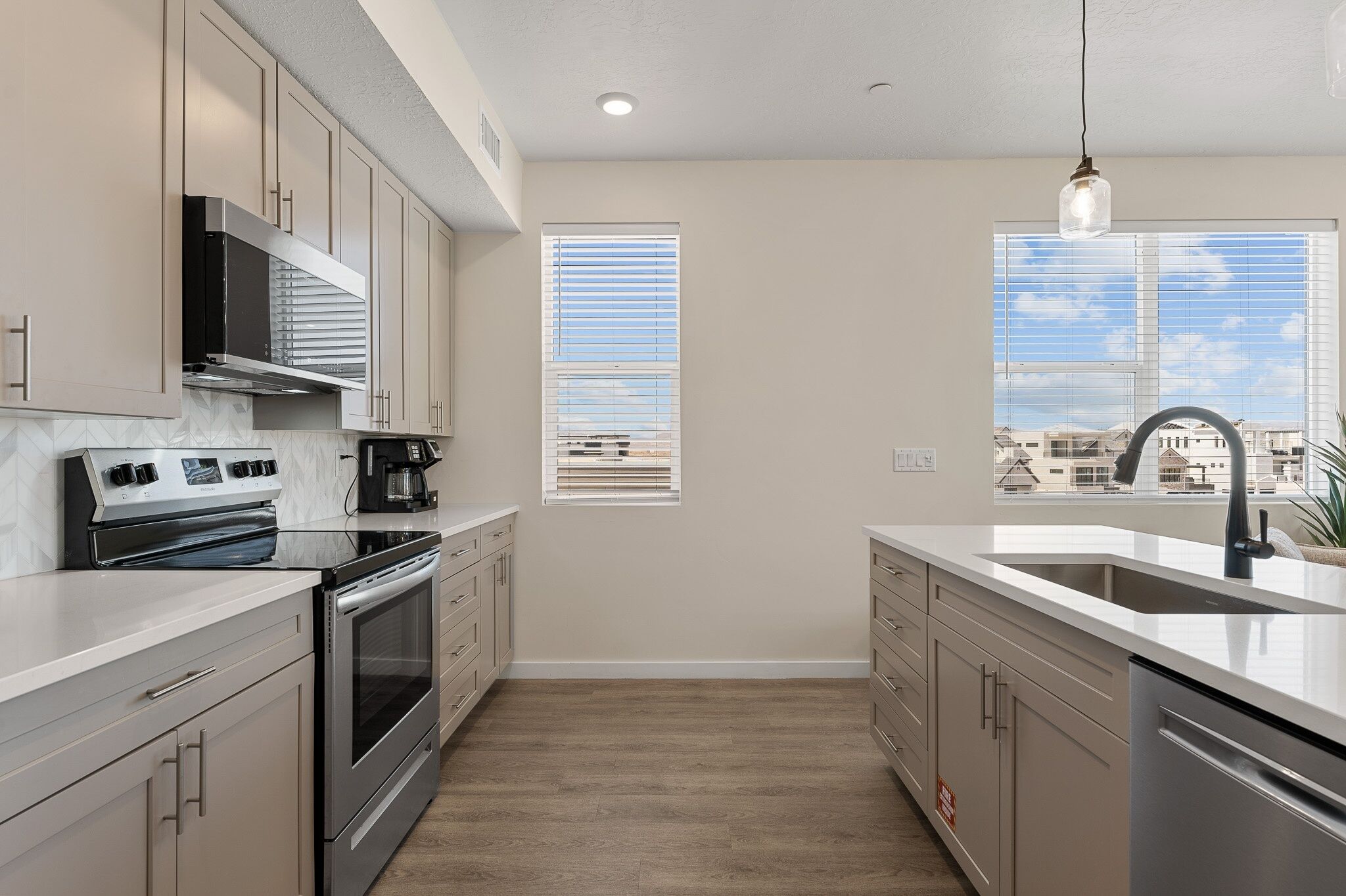 A modern kitchen with stainless steel appliances, white cabinetry, and a large window providing a view of the cityscape.