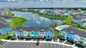 A residential area with colorful houses, a lake, and a parking lot. - Surfstyle At Margaritaville By Shine Villas 022 3 Bedroom Villa (Kissimmee)