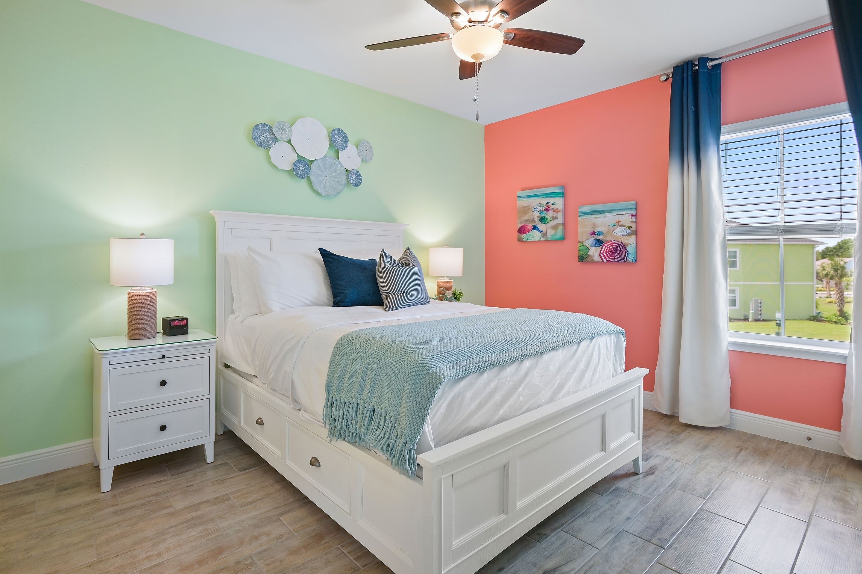 A bedroom with a bed, nightstands, a ceiling fan, and a window with curtains.