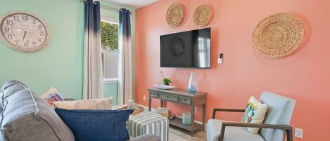 Una sala de estar con un sofá, un sillón y un televisor montado en la pared.