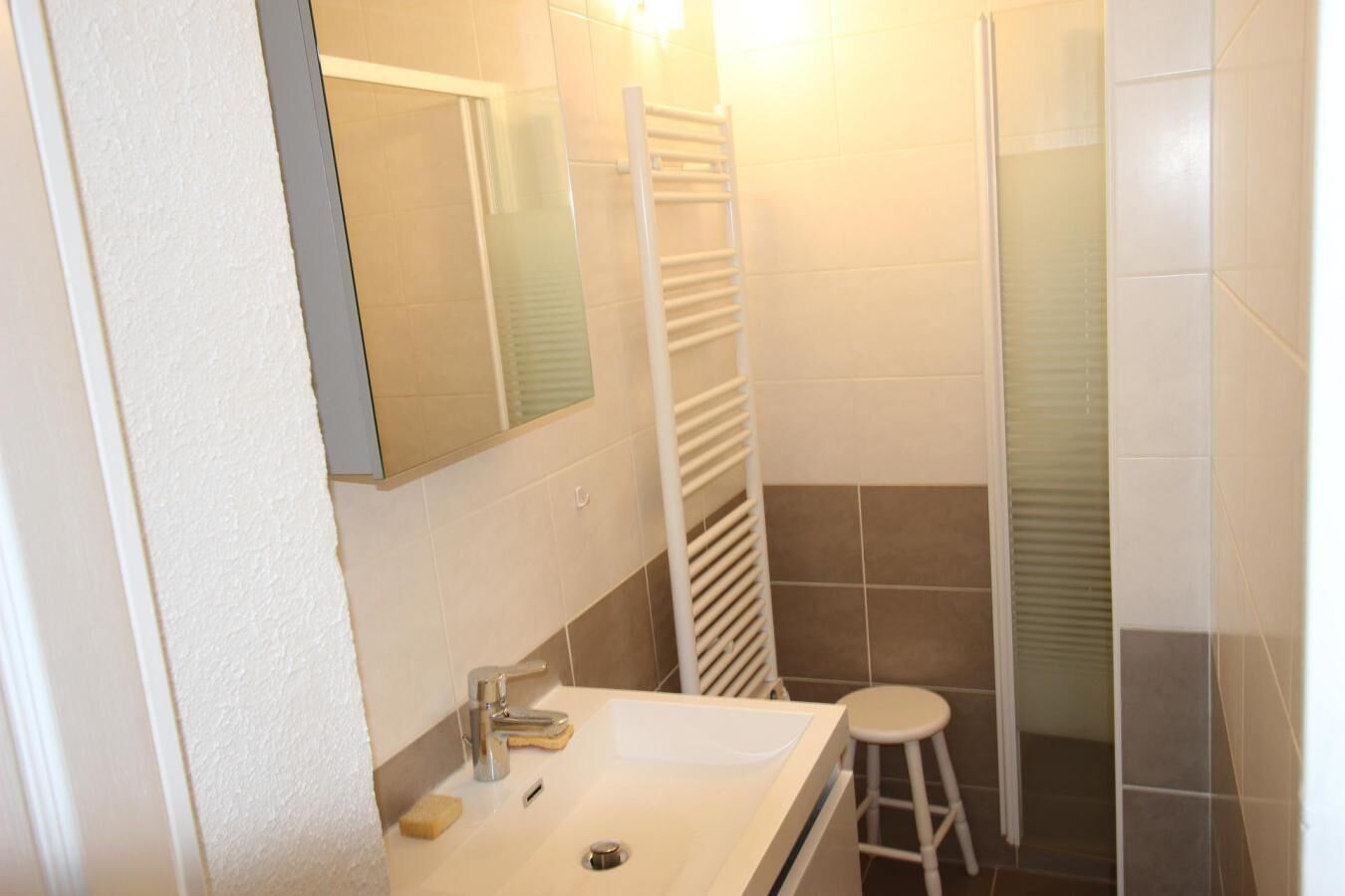 Une salle de bain équipée d’un lavabo, d’un miroir, d’un porte-serviettes et d’un espace douche.