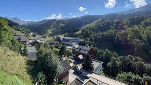 A mountainous village with a prominent building in the center, surrounded by houses and lush greenery. - 150m from ski slopes, 5th floor, view resort, balcony, tv, 55m², Méribel (Méribel - Les Allues)