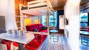 A cozy room with a bunk bed, a red sofa, a small table, and a TV.
