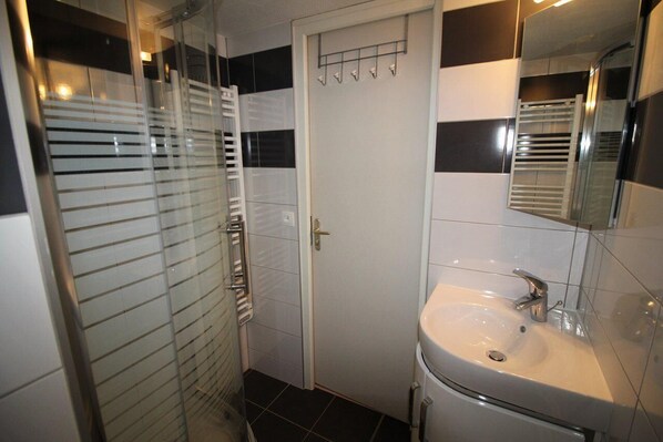 A bathroom with a glass shower enclosure, a white sink, and a mirror above it.