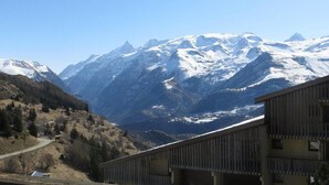 Eine Berglandschaft mit schneebedeckten Gipfeln und ein Gebäude mit Schindeldach im Vordergrund.