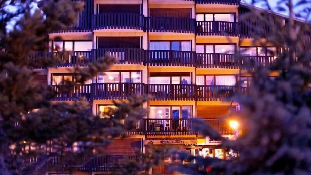 Un hotel de varios pisos con balcones y un restaurante en la planta baja.