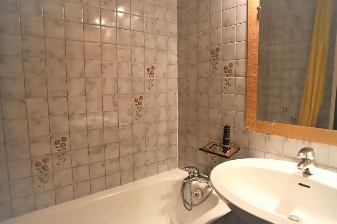 A bathroom with a white sink, a mirror, and a shower.