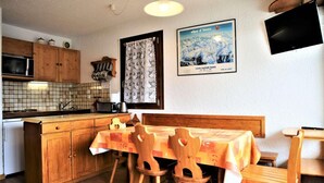 Una cocina acogedora con armarios de madera, salpicadero de azulejos, una mesa de comedor con sillas y un póster enmarcado en la pared.