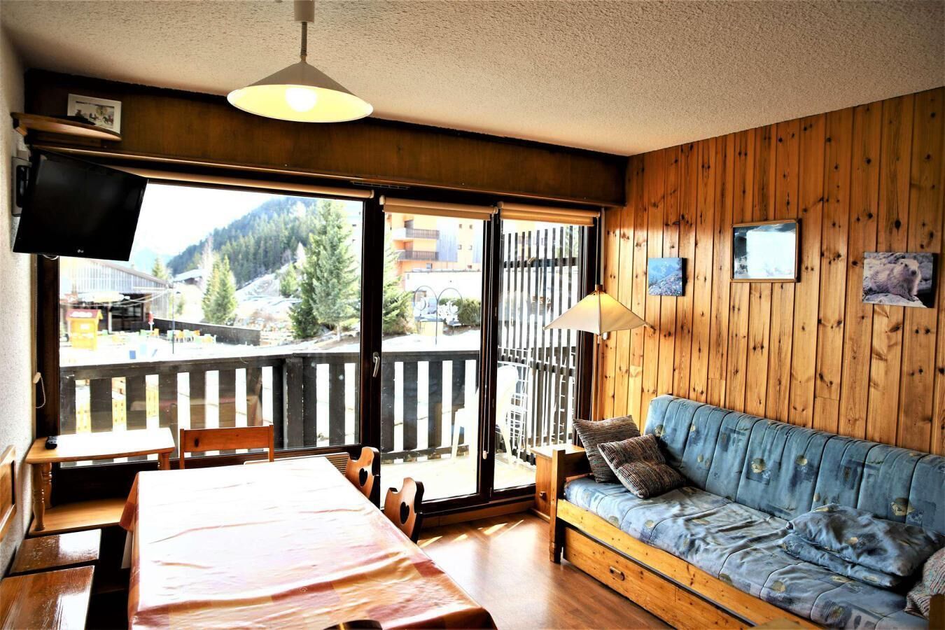 A cozy room with a wooden floor, a sofa, a table, and a TV.