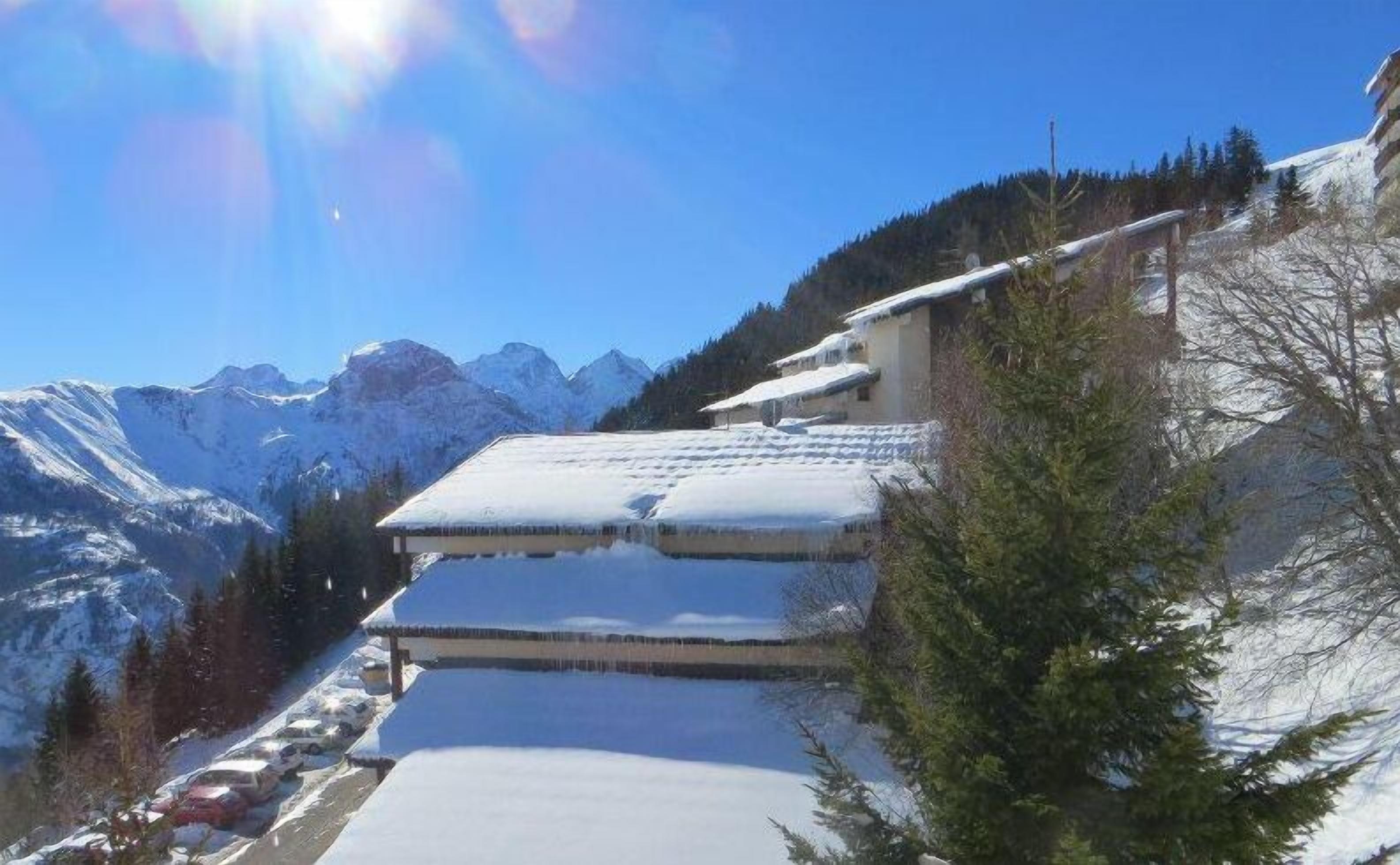 A snow-covered mountain landscape with a building featuring a sloped roof and a clear view of the surrounding mountains.