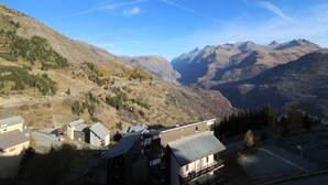 Bergachtig landschap met een woongebied, huizen met schuine daken, een heldere lucht en zichtbare elektriciteitskabels.