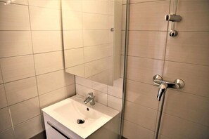 A bathroom with a white sink, a mirror, and a shower with a handheld showerhead. - 10m from ski slopes, 2nd floor, balcony, tv, ski locker, 23m², Auris en Oisans (Auris)