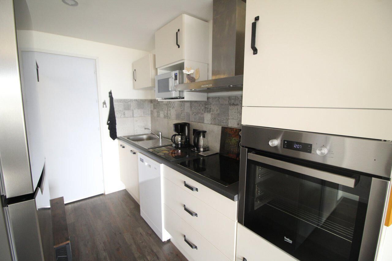 A modern kitchen with white cabinets, a black countertop, a stainless steel oven, and a dishwasher.