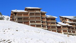 Useita kerroksia käsittävä hotelli, jossa on parvekkeet, ja jonka taustalla avautuu lumipeitteinen maisema.