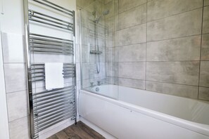 Een bad/douchecombinatie, handdoeken