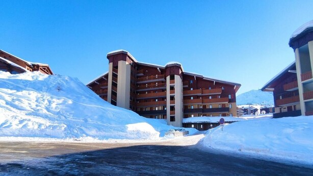 A multi-story hotel with a snow-covered ground and a clear blue sky. - 50m from ski slopes, 4th floor, view ski slopes, balcony, parking, tv, 29m², La Plagne (La Plagne)