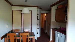 A compact kitchen with a refrigerator, microwave, and sink. There is a dining area with a table and chairs. - 50m from ski slopes, 4th floor, view ski slopes, balcony, parking, tv, 29m², La Plagne (La Plagne)