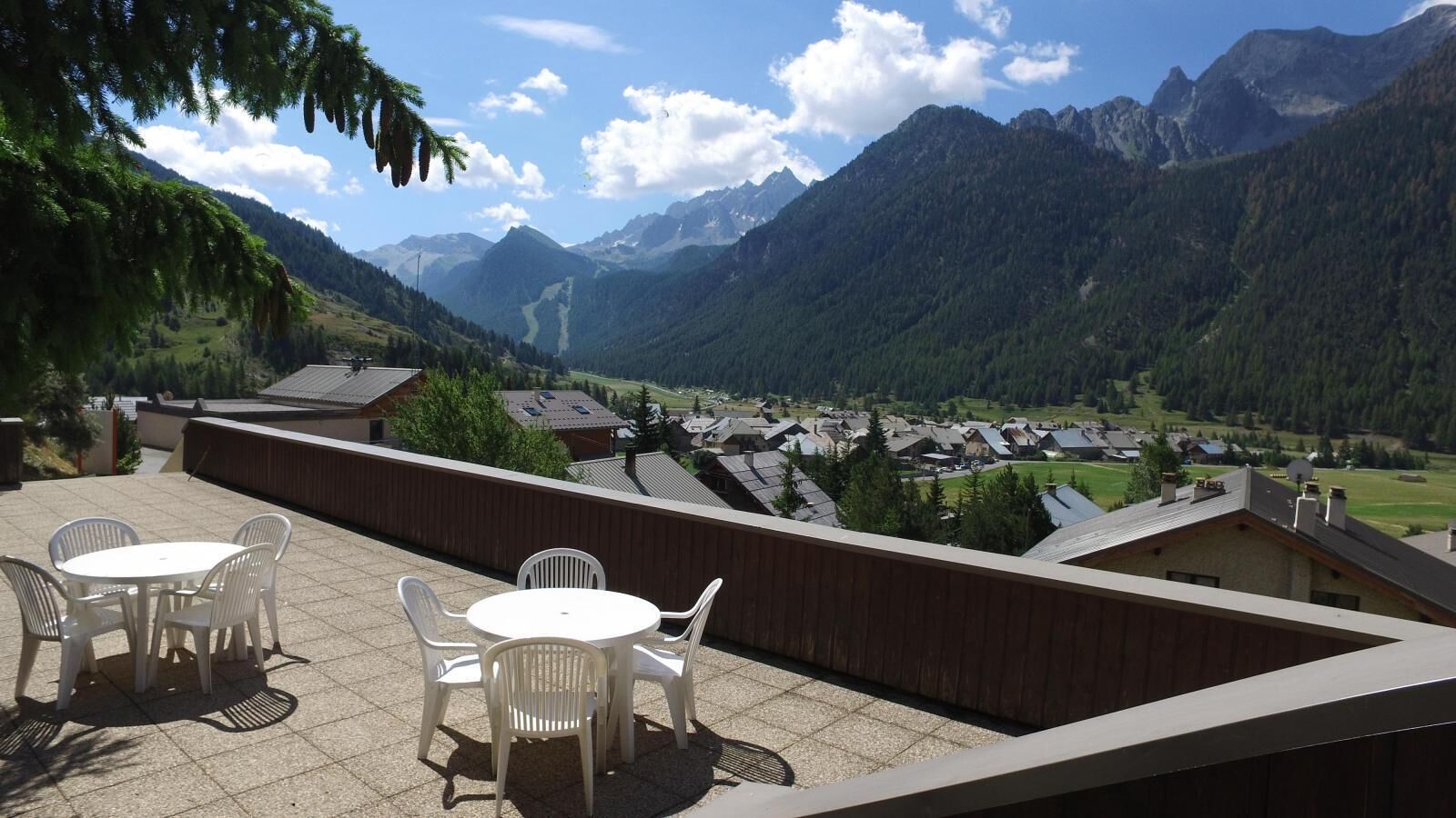 A terrace with a table and chairs overlooking a mountainous landscape.