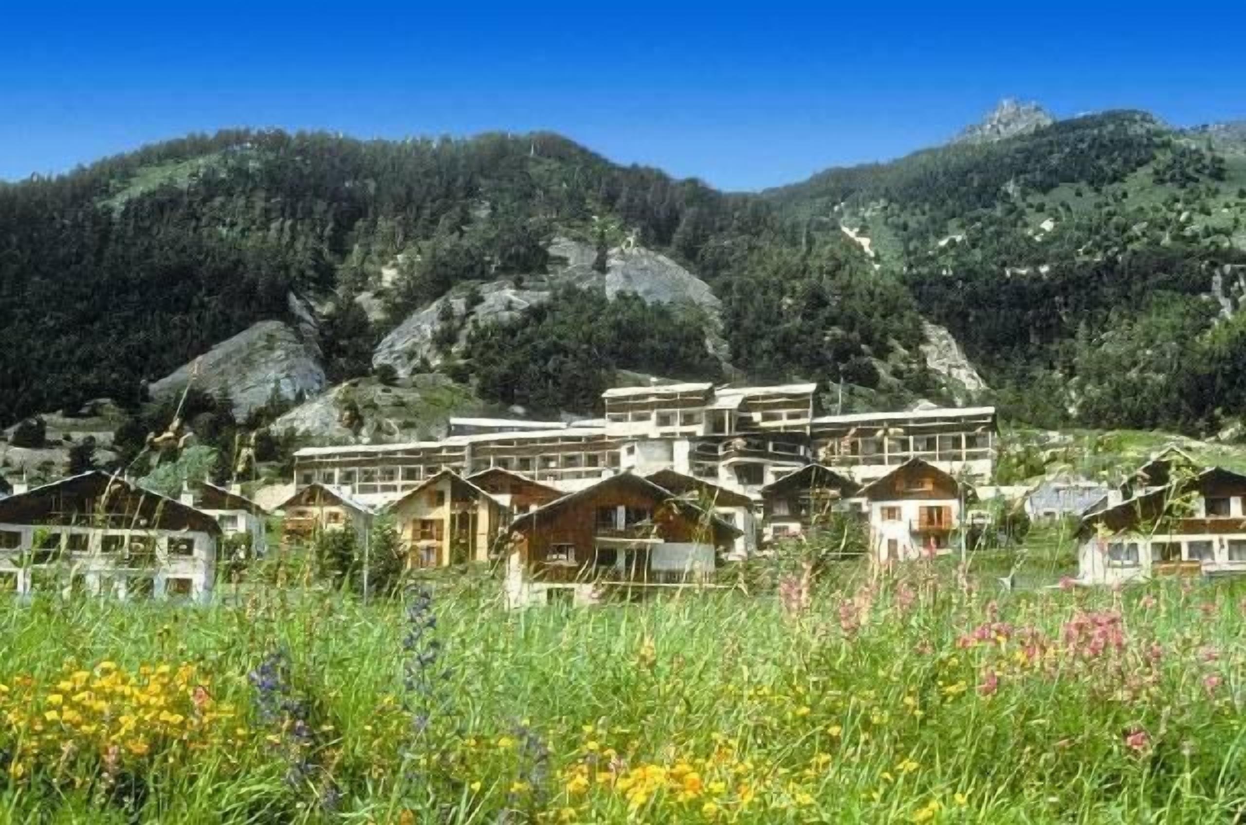 A cluster of wooden chalets with a mountain backdrop.