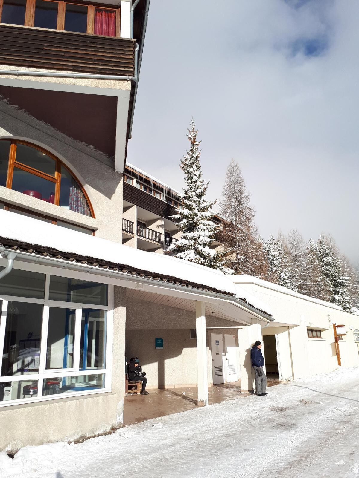 A multi-story building with a covered entrance and a snow-covered landscape.