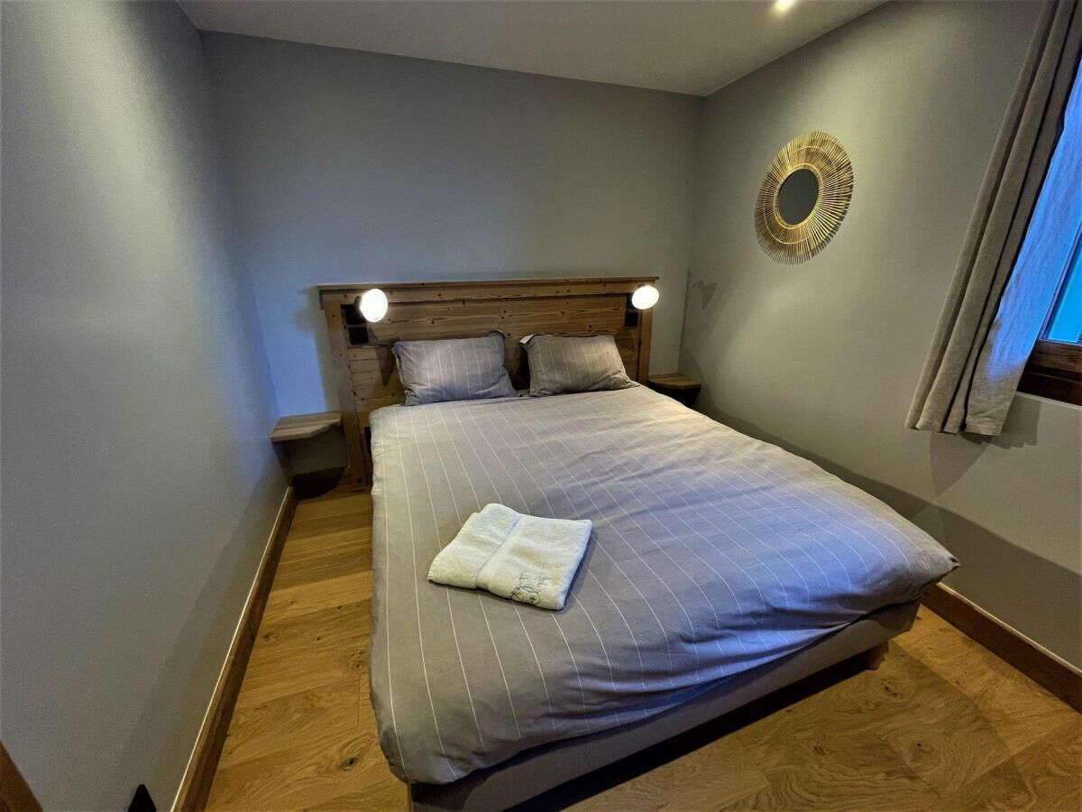 A neatly made bed with a striped bedspread and pillows, a wooden headboard, bedside lamps, and a circular wall decoration.
