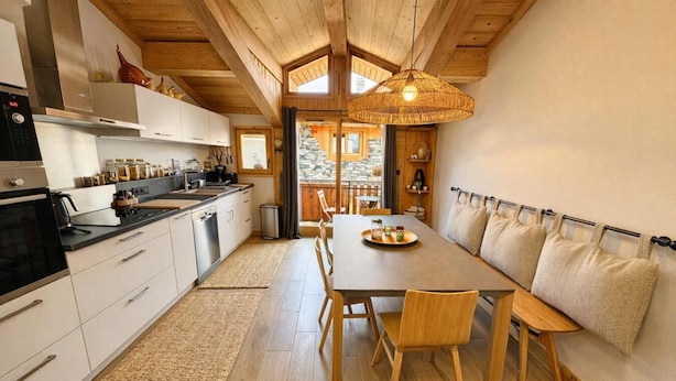 Une cuisine moderne avec des meubles en bois, une grande table à manger et un luminaire suspendu.