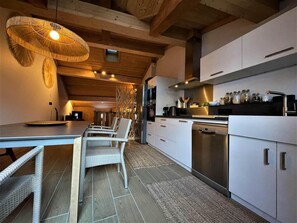 A modern kitchen with white cabinets, stainless steel appliances, and wicker furniture.