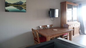 A dining area with a wooden table and chairs, a television mounted on the wall, and a cabinet with a window. - Ski-in/ski-out & foot of the slopes, 6th floor, view mountain, balcony, tv, 60m², Les Orres (Les Orres)