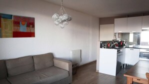 A modern living room with a beige sofa, a dining table, and a kitchen area with white cabinets and stainless steel appliances. - Ski-in/ski-out & foot of the slopes, 6th floor, view mountain, balcony, tv, 60m², Les Orres (Les Orres)