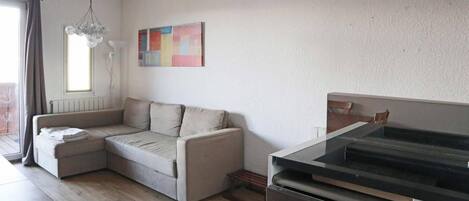 Una sala moderna con un sofá seccional, una mesa de comedor y una cocina con estufa.