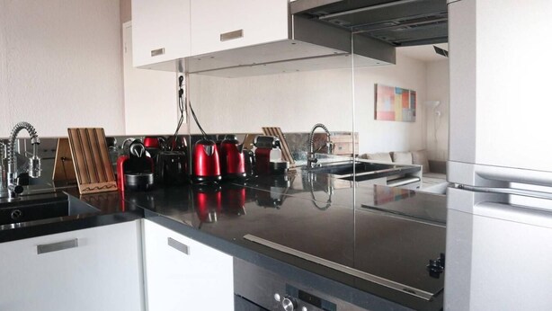 A modern kitchen with stainless steel appliances, a black countertop, and a wooden cutting board. - Ski-in/ski-out & foot of the slopes, 6th floor, view mountain, balcony, tv, 60m², Les Orres (Les Orres)