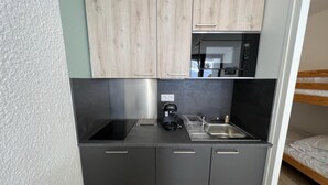 Een kleine keuken met een magnetron, koffiezetapparaat en spoelbak.