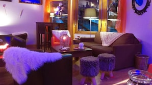 Un salon chaleureux avec un canapé, des poufs, une table basse et une lanterne décorative.