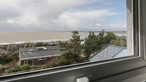 A coastal view from a window overlooking a beach, houses, and a bridge. - Tŷ Glas (Bridgend)