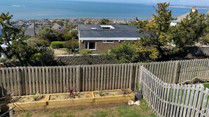 A residential area with a view of the ocean, a house with a sloped roof, and a wooden fence. - Tŷ Glas (Bridgend)