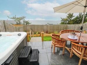 Un jacuzzi, terraza de madera y zona de estar al aire libre con vistas al mar.