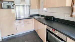 A modern kitchen with beige cabinetry, a stainless steel range hood, a toaster, and a dishwasher. - 1st floor, balcony, tv, ski locker, 58m², Tignes (Tignes)