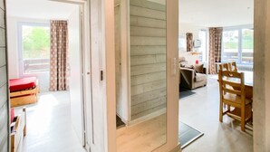 A spacious living area with a wooden floor, a sofa, a dining table, and a red bench. - 1st floor, balcony, tv, ski locker, 58m², Tignes (Tignes)