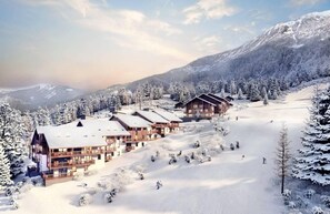 Eine schneebedeckte Lodge mit mehreren Holzhäusern, umgeben von schneebedeckten Bäumen und Bergen.
