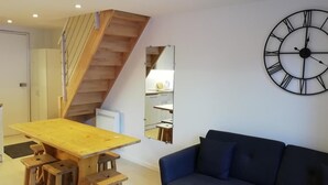 Ein modernes Interieur mit einem Holztisch, einem blauen Sofa und einer großen Wanduhr.